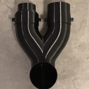 Op de afbeelding: Zwarte Y-vormige kunststof buis met twee ronde inlaten en één ronde uitlaat.