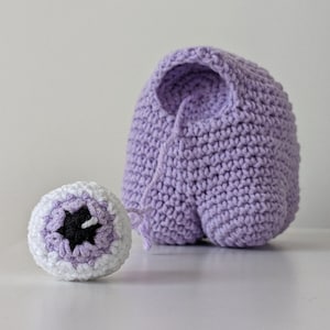 May include: A crocheted purple plush toy shaped like a character from the video game Among Us. The toy has a white eye with a black pupil.