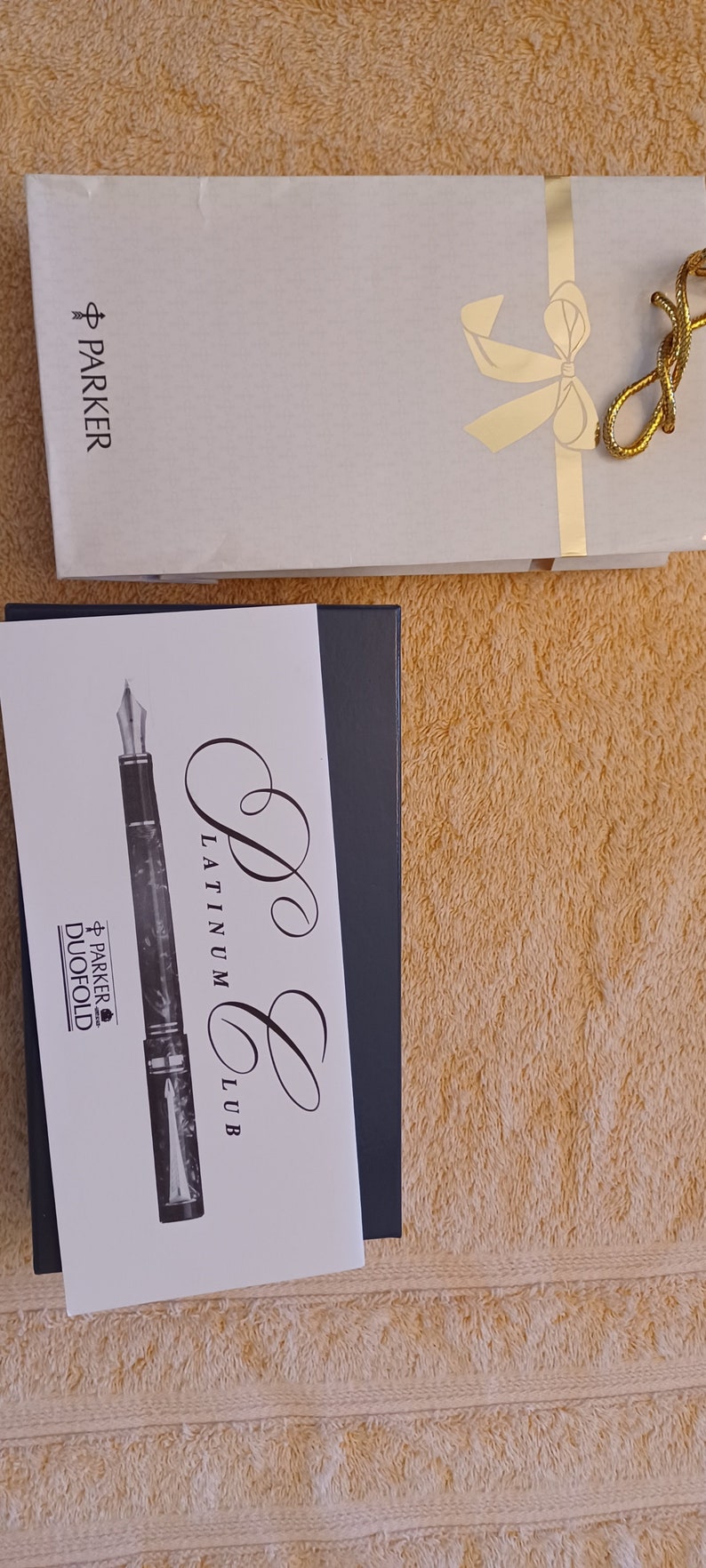 Puede incluir: Una imagen en blanco y negro de una pluma estilogr&aacute;fica Parker Duofold con un dise&ntilde;o de m&aacute;rmol. La pluma est&aacute; en una caja con las palabras "Parker Platinum Club" escritas en ella.