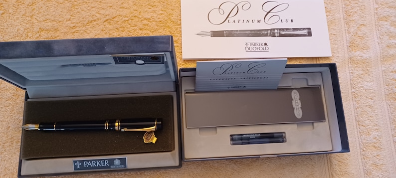 Puede incluir: Una pluma estilogr&aacute;fica Parker Duofold negra y dorada en su caja original. La pluma forma parte de la colecci&oacute;n Platinum Club. La caja incluye dos cartuchos de tinta.