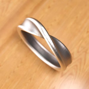 May include: A silver twisted band ring with a brushed finish.