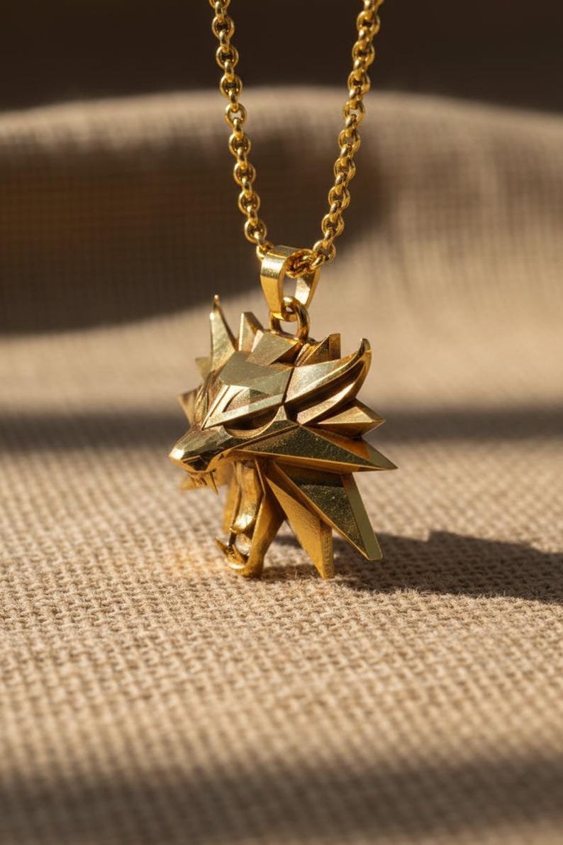 May include: A gold-colored pendant necklace featuring a stylized wolf head. The pendant has a geometric design with sharp angles and is suspended from a matching chain. The necklace is displayed against a neutral background.