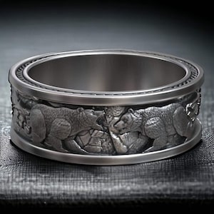 May include: A silver ring with a detailed design of two bears facing each other. The bears are sculpted in a realistic style and appear to be in a confrontation.