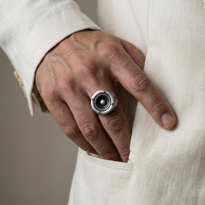 A close-up of a person's hand wearing a ring with a silver-colored metal ring on the finger.