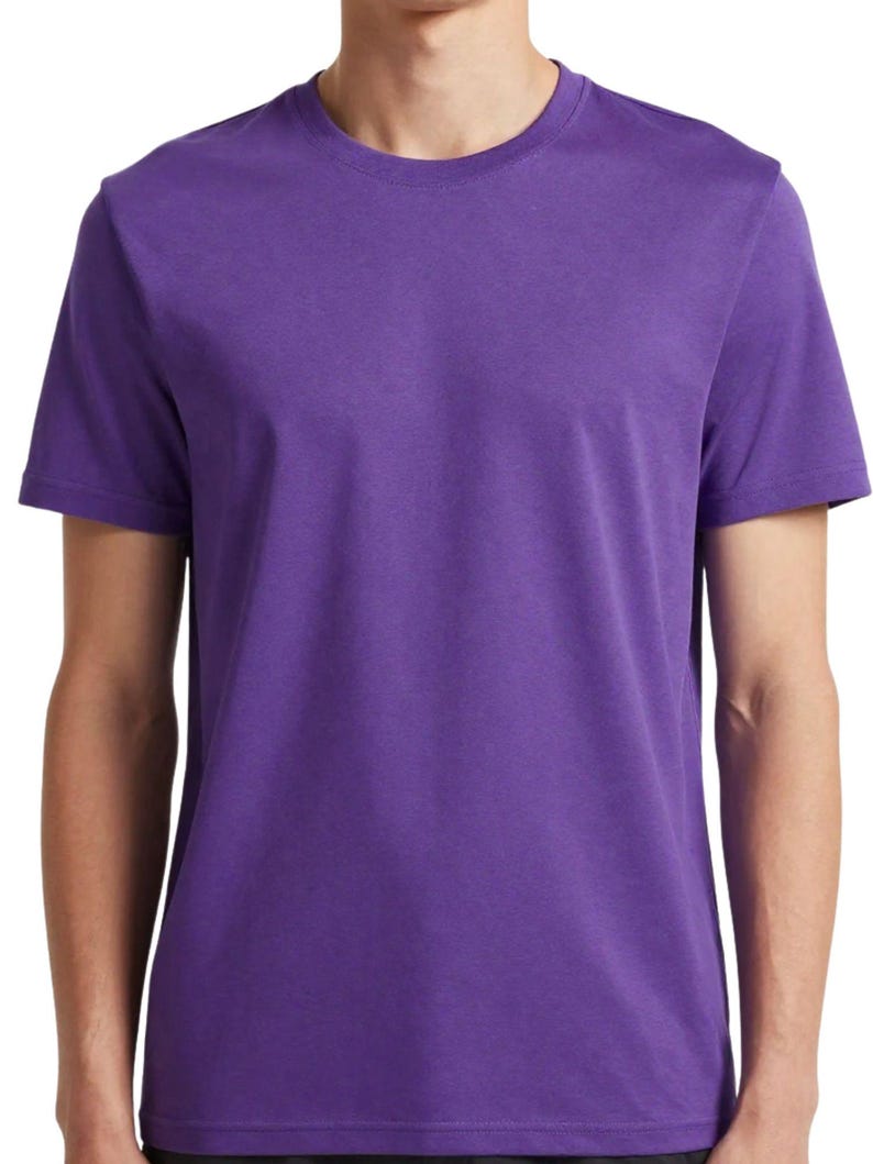 Puede incluir: Una camiseta lisa de color morado con cuello redondo. La parte superior de manga corta est&aacute; hecha de un material suave y tiene un dise&ntilde;o sencillo. La camisa es de un tono morado vibrante.