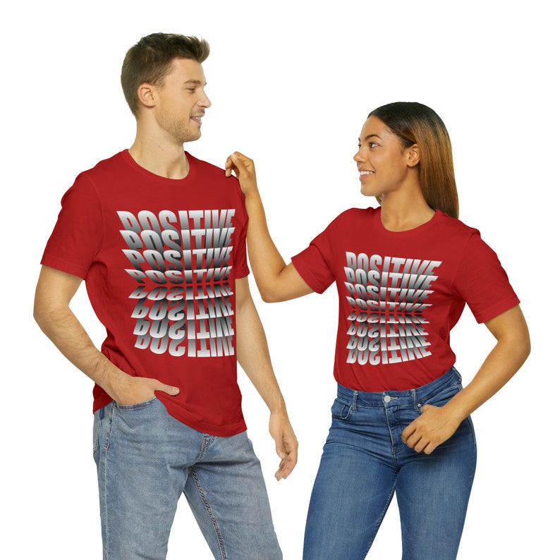 May include: Two people wearing red t-shirts with the word "POSITIVE" printed in a gradient of gray and white. The word is repeated multiple times on each shirt, with each repetition slightly offset from the one above it.