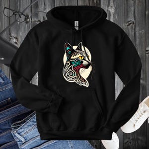 May include: Black hoodie with a colorful abstract cat design on the front. The cat's eyes are yellow and the design is in shades of blue, green, red, and black.