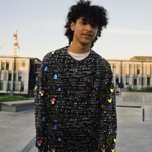 May include: A black long-sleeve shirt featuring an all-over print of white mathematical equations, formulas, and geometric diagrams, accented with small, colorful shapes in blue, red, and yellow throughout the fabric pattern.