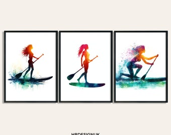 May include: Set of three watercolor prints featuring a silhouette of a person paddleboarding. The prints are in shades of blue, green, orange, and red.