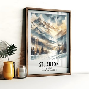 May include: A watercolor painting of a mountain landscape with a ski lift in the foreground. The painting is framed in a brown wood frame. The text "ST. ANTON" is printed below the image, along with the coordinates "47.1296° N, 10.2682° E" and the word "AUSTRIA".