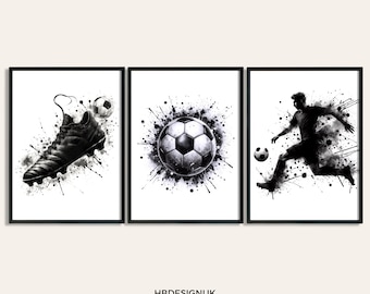 May include: A set of three framed art prints featuring black and white watercolor-style illustrations of soccer themes: a cleat, a soccer ball, and a player in motion. Each print displays dynamic ink splatters and the text HBDESIGNUK ART PRINTS ON ETSY.