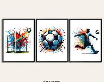 May include: Set of three framed art prints featuring soccer themes. One print shows a soccer goal with a ball, another a soccer ball with colorful splatter, and the third a soccer player kicking the ball. The prints have a white background and black frames.