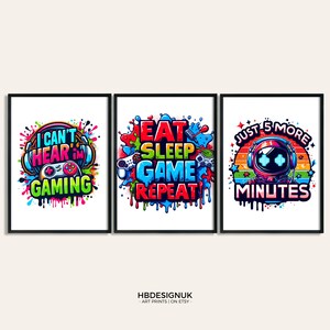 Op de afbeelding: Drie kleurrijke ingelijste prints met gamer-thema tekst en afbeeldingen. De eerste print zegt "Ik kan niet horen, ik game" met een gamecontroller en koptelefoon. De tweede print zegt "Eten Slapen Gamen Herhalen" met een gamecontroller en een joystick. De derde print zegt "Nog 5 minuten" met een robot die een koptelefoon en een gamecontroller draagt.