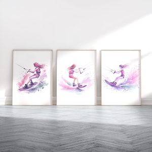 May include: Three framed watercolour paintings of women wakeboarding. Each painting features a woman in a pink life vest and pink shorts wakeboarding on a blue and purple wave. The background of each painting is a white wash of watercolour.