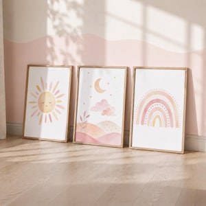 Puede incluir: Tres láminas decorativas rectangulares en marcos de madera clara. La primera muestra un sol sonriente con rayos rosas y amarillos. La segunda presenta una luna creciente, estrellas, nubes y colinas. La tercera muestra un arcoíris multicolor.