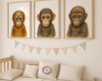 May include: Three framed prints of baby primates, each with a different species. The prints are hung on a white wall above a wooden crib with a white and gray patterned bedding. The crib has a white pillow with a watercolor floral wreath and the initials "HB" in the center.