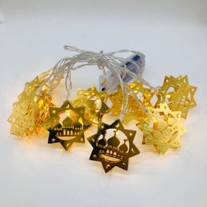 May include: A string of 10 gold star-shaped LED lights with a mosque design. The lights are battery-operated and perfect for Ramadan decorations.