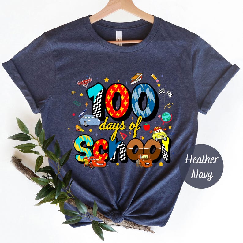 A blue t-shirt with a colorful graphic design that says "100 days of school" and features various cartoon characters and objects associated with education.