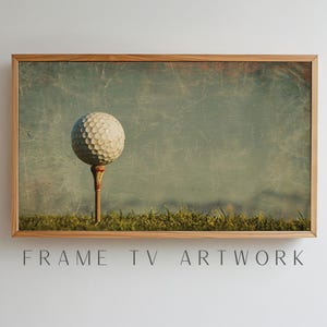 May include: A white golf ball sits on a tee, set against a green grassy background with a faded, textured blue sky. The image has a vintage, distressed look.