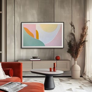 May include: A modern living room with a flat screen TV displaying an abstract painting with pink, green, yellow, and white colors. The TV is mounted on a wall above a wooden cabinet with a vase of dried flowers and a coffee table with a bowl and candles.
