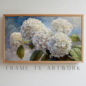 May include: A framed painting of white hydrangea flowers with green leaves against a blue and white backdrop. The artwork is in a light brown wooden frame. The text "FRAME TV ARTWORK" is at the bottom of the image.