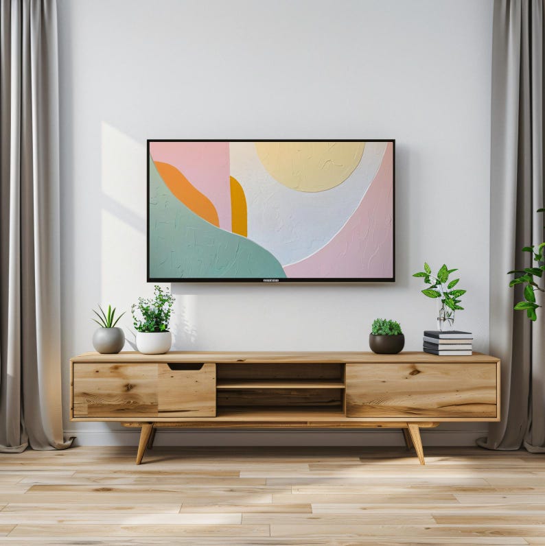 May include: A wooden TV stand with a light wood finish. The stand has two drawers and two open shelves. A flat screen TV is mounted on the wall above the stand. The TV is displaying an abstract painting with pink, yellow, orange, and green colors.