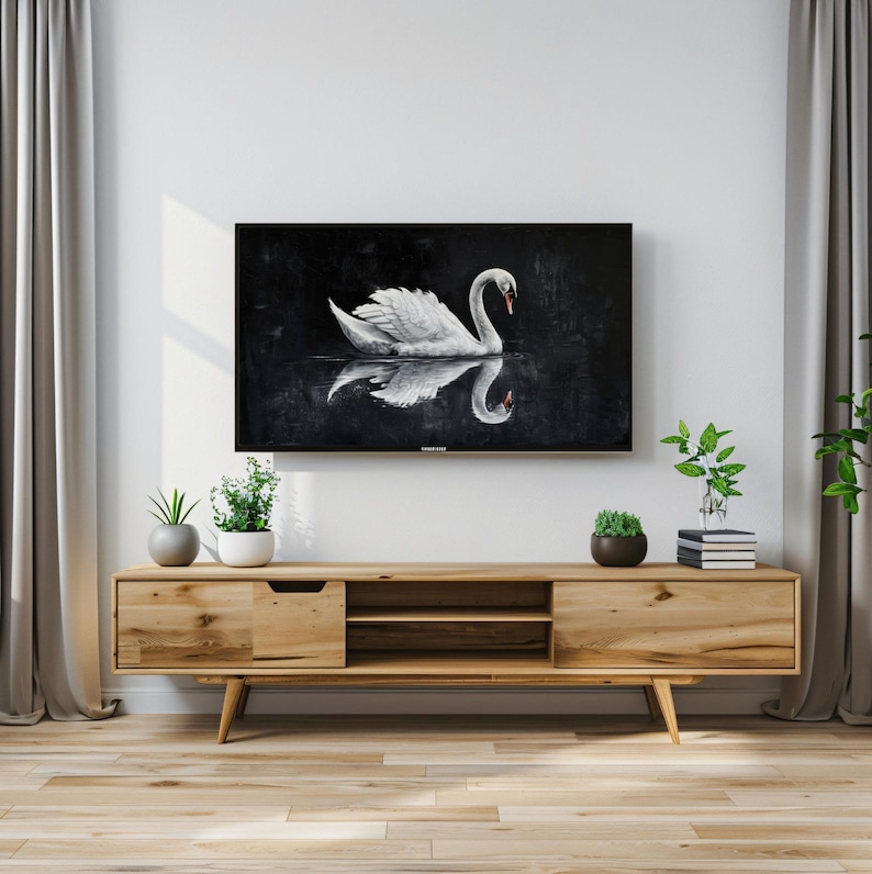 K&ouml;nnte beinhalten: Ein wei&szlig;er Schwan mit seiner Spiegelung im Wasser, gemalt auf einer schwarzen Leinwand. Das Gem&auml;lde wird auf einem Fernsehbildschirm angezeigt, der an einem h&ouml;lzernen Unterhaltungszentrum montiert ist.