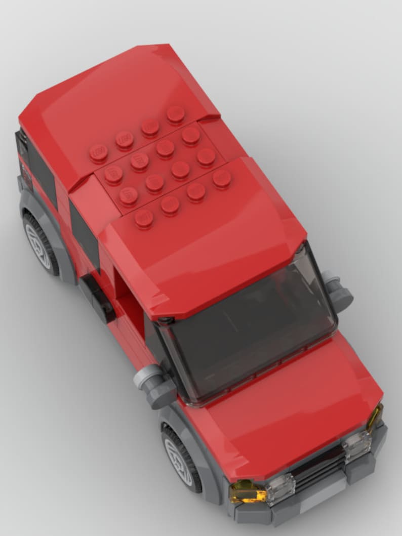 K&ouml;nnte beinhalten: Ein rotes Spielzeugauto mit einer schwarzen Windschutzscheibe und grauen R&auml;dern. Das Auto hat ein abnehmbares Dach mit einem Muster aus roten LEGO-Steinen.