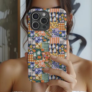May include: A smartphone case featuring a patchwork design of various squares. The pattern includes white ghosts, orange pumpkins, small yellow and purple flowers, green and white gingham, and orange plaid squares on a dark blue background.