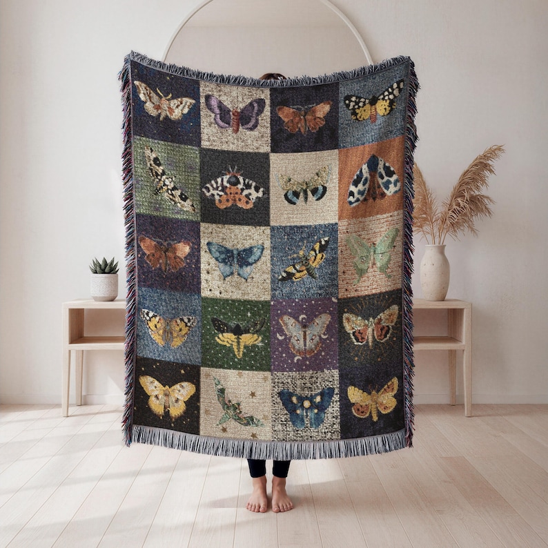 Celestial moth woven blanket held up by a woman in neutral living room