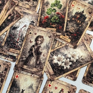 May include: A collection of vintage-style oracle cards featuring aged, sepia-toned paper with intricate illustrations. Visible cards include the Child with the number 13, Clover with the number 2, House with the number 4, Stork, and Lilies.
