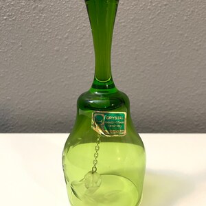 May include: A green glass bell with a chain and a small ball at the end. The bell has a label that reads "Crystal Mouth-blown Venice Italy".