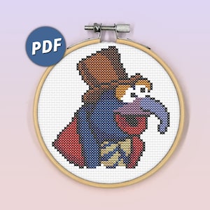 Può includere: Schema di punto croce di un personaggio Muppet viola che indossa un cappello marrone e una giacca rossa e blu. Il personaggio ha un naso lungo e sorride.