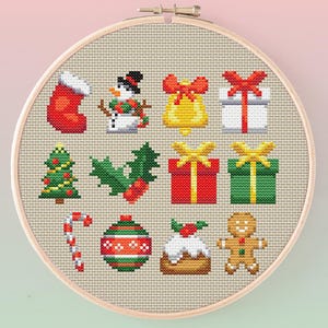 May include: A cross-stitch embroidery hoop featuring various Christmas-themed icons. The design includes a red stocking, snowman, bell, wrapped gifts, Christmas tree, holly, candy cane, ornament, pudding, and gingerbread man.