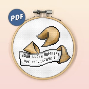 May include: A cross-stitch pattern featuring three fortune cookies and a fortune cookie slip that reads "Your lucky numbers are 1234567890."