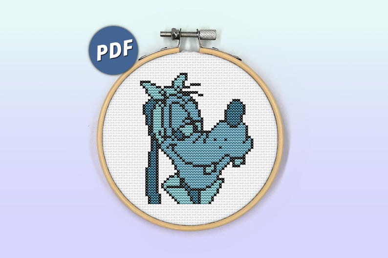 May include: A cross stitch pattern featuring a light blue cartoon dog character with a dark blue nose and ears, stitched on white fabric held within a round wooden embroidery hoop. A blue circular icon with the white text PDF is visible.