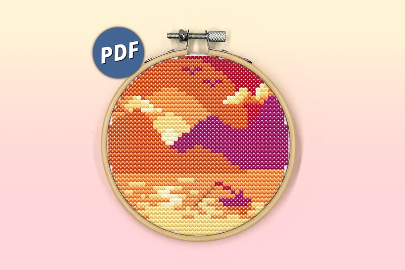 K&ouml;nnte beinhalten: Ein Kreuzstichmuster in einem h&ouml;lzernen Stickrahmen, das eine Sonnenuntergangslandschaft mit orangefarbenen, gelben und dunkelmagentafarbenen Wolken zeigt. Das Design hat eine pixelige &Auml;sthetik. Ein blaues kreisf&ouml;rmiges Symbol mit dem Text PDF ist zu sehen.