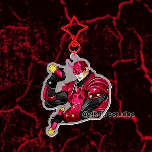 Puede incluir: Un llavero de acrílico que muestra a un personaje con armadura roja y negra con cuernos, sosteniendo un par de nunchakus. El llavero tiene un cierre rojo en forma de estrella e incluye el texto @starfyrestudios en la parte inferior derecha.