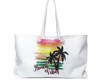 May include: White canvas tote bag with a watercolor sunset and palm trees design. The text "Beach Vibes" is printed in pink on the bag.
