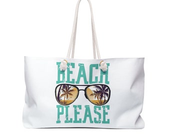 May include: White beach tote bag with a rope handle. The bag features the words "BEACH PLEASE" in teal block letters, with a graphic of sunglasses reflecting a beach scene. The bag is designed for carrying beach essentials.