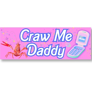 Op de afbeelding: Een roze banner met de tekst "Craw Me Daddy" in blauwe letters. Aan de linkerkant van de banner staat een cartoon-kreeft en aan de rechterkant een roze klaptelefoon met het woord "daddy" op het scherm.
