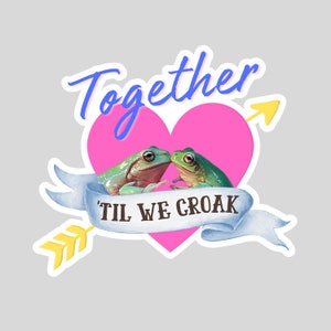 May include: A pink heart with two green frogs kissing inside. The heart has a blue ribbon with the text "Til We Croak" and a yellow arrow pointing to the right.