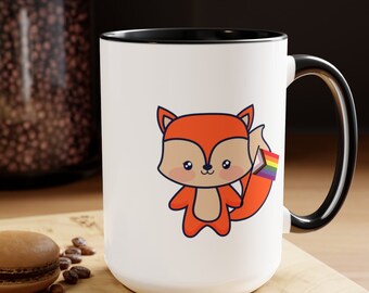 May include: White ceramic mug with a black rim and handle. The mug features a cartoon fox with an orange body and a rainbow flag in its tail.