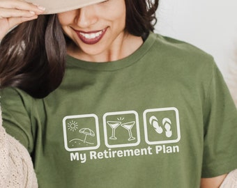 May include: A green t-shirt with a white graphic design of three icons. The icons depict a beach umbrella, two cocktail glasses, and a pair of flip flops. The text "My Retirement Plan" is below the icons.