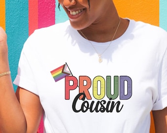 May include: White t-shirt with a rainbow flag and the text "PROUD COUSIN" in rainbow colors.