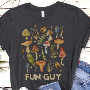 May include: A dark gray t-shirt with a colorful mushroom graphic and the text "FUN GUY" printed on the front.