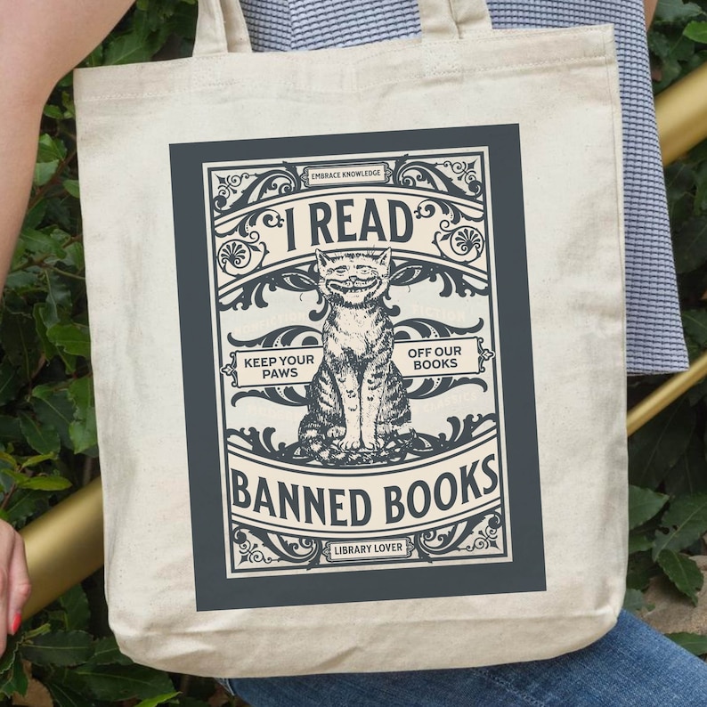 May include: A white canvas tote bag featuring a black and white illustration of a cat with the text "I Read Banned Books" in a vintage style. The text "Embrace Knowledge" and "Library Lover" are also included in the design.