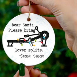 May include: White ceramic Christmas ornament with a black and white illustration of a person on a rowing machine with Christmas lights. The text reads "Dear Santa, Please bring lower splits. ~Coach Susan"