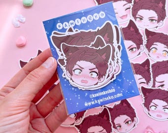 May include: A collection of die-cut vinyl stickers featuring an anime-style character with brown hair and cat ears. The stickers are packaged in a blue sleeve with the text KAWINEKO, @kawinekoshop, and www.kawineko.com printed in white.