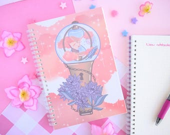 May include: Two spiral bound notebooks with pink covers. The notebook on the left has a pink and white illustration of a light bulb with a keyhole and a chain. The notebook on the right has the words "New notebooks!" written on the cover.